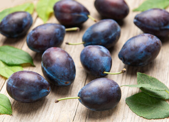 Ripe purple plums fallen on wooden table