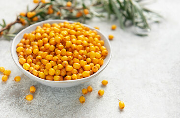 Sea buckthorn berries in bowl with branches
