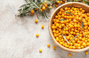 Sea buckthorn berries filling wooden bowl on table