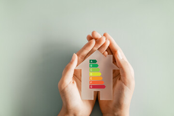 Hands holding house with house efficiency rating, ecological house, sustainable development concept
