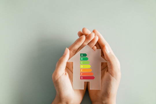 Hands holding house with house efficiency rating, ecological house, sustainable development concept
