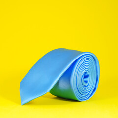 necktie rolled on yellow background close-up view 