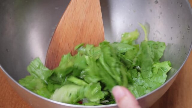 ボウルの中のサラダを木べらで混ぜる｜レタスとトマトのサラダ