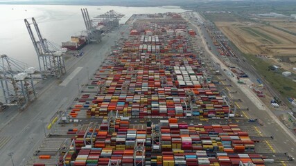 Drone footage of shipping port in London showing container stacks, cranes, and vessels on the River Thames, London UK
 - Powered by Adobe