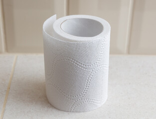 A roll of toilet paper is sitting on a white tile floor