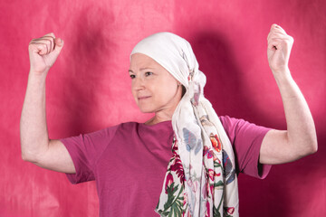 A woman with her arms raised in a strong posture. She has breast cancer, and strength is one of the...