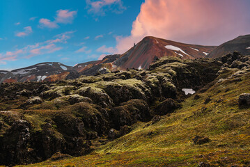Moss covered lava fields lead to rhyolite mountains with snow in Landmannalaugar, Iceland. Warm...