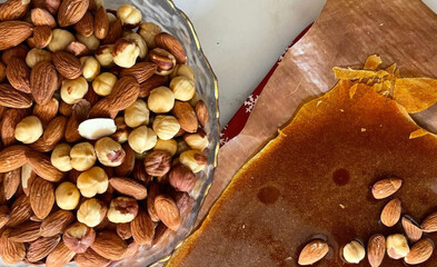 Assorted nuts cascade like autumnal confetti beside golden brittle, evoking Harvest Festival, Diwali essence, indulgent crunch delight