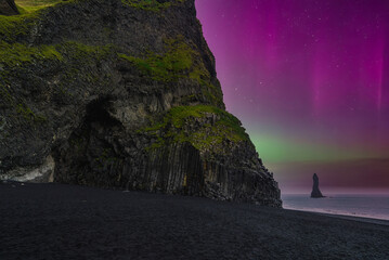 Night view at Reynisfjara near Vik i Myrdal, Iceland shows basalt columns, black sand, and...