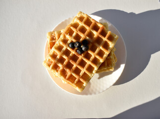 Stack of Belgian waffles topped with blueberries on white top view