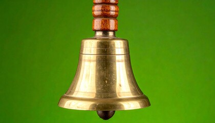 Classic brass hand bell with polished wooden handle on vibrant green screen background