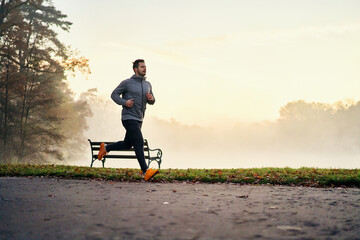 Active man running on foggy morning during autumn