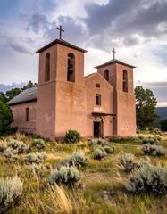 Old adobe church at dusk under a moody sky with twin bell towers