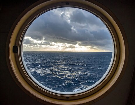 An eye-shaped window frames a view of the sea with dramatic, stormy clouds and a break in the sun rays