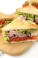 Tasty sandwiches with ham and vegetables on white wooden table, closeup