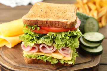 Tasty sandwich with ham, cheese and vegetables on wooden table, closeup