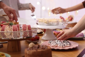People taking different desserts from buffet table, closeup