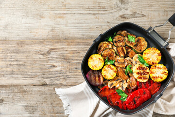 Delicious grilled vegetables, mushrooms and parsley in pan on wooden table, top view. Space for text