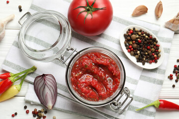 Tasty salsa sauce in jar and ingredients on white wooden table, flat lay