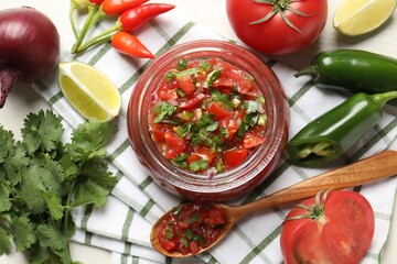 Tasty salsa in jar and ingredients on white table, flat lay