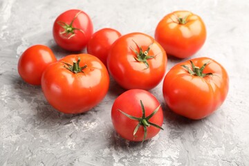 Fresh ripe tomatoes on grey textured table, closeup