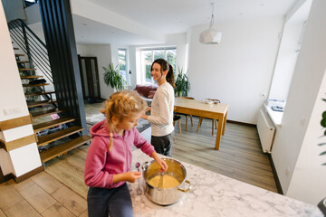Woman cooking food indoors with a kid