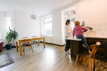 Woman cooking food indoors with a kid
