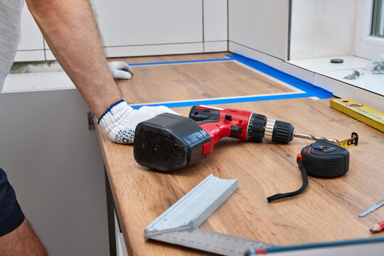repairman working on a new kitchen installation and using electric drill