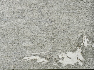 Granite-like stone surface in gray tones with rough texture and lighter inclusions. Close-up. Copyspace.