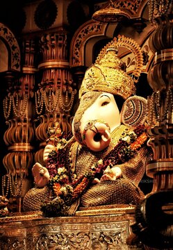Golden adorned idol of Lord Ganesha at Dagdusheth Ganapati temple, Pune. The statue is richly decorated with garlands and ornaments, symbolizing devotion and cultural grandeur.