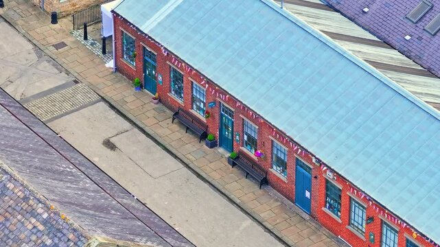 Drone view of restored Victorian workshop at Elsecar Heritage Centre, showing brick architecture and courtyard layout, located in Barnsley, South Yorkshire, England.