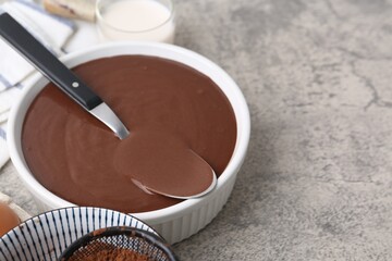 Liquid chocolate dough in bowl on grey table, closeup. Space for text