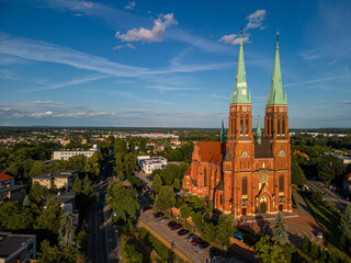 Aerial view historic Basilica Saint Anthony Rybnik, Poland, vertical composition, evening sunlight, neo-Gothic brick architecture, twin towers, urban park, tourism, editorial use
