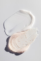 Pink body scrub and white moisturizing cream texture on a clean surface, minimal beauty composition.