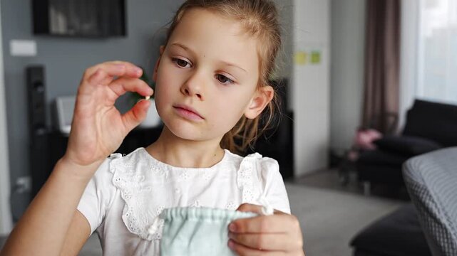 Little girl placing her baby tooth into a small pouch for the tooth fairy. Capturing a tender childhood ritual filled with imagination and meaning.