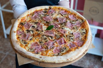 Homemade italian pizza in hand with ham and mushhrooms tasty big