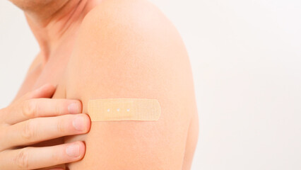 Close-up of a man's shoulder with adhesive bandage after vaccination or injection