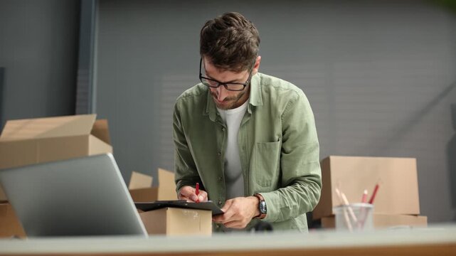 A man is sitting at a desk with a laptop and a clipboard