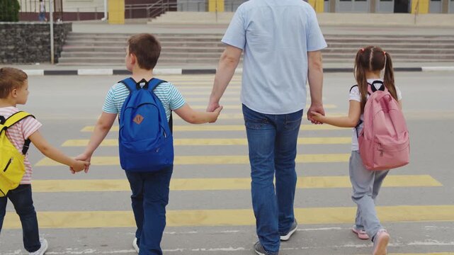 Group of students with dad, Early school drop off, Safety first at crosswalk, Children united with parent, School day starts, Colorful backpacks, Street safety awareness, Pedestrian family crossing