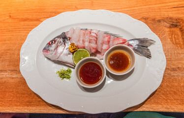 Freshly prepared fish dish with garnishes and dipping sauces on plate