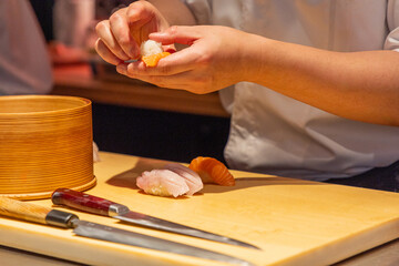 Sushi chef preparing fresh sushi rolls on wooden cutting board