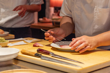 Skilled chef preparing sushi with precision on wooden cutting board