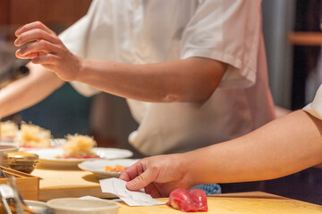 Obraz premium Chef preparing sushi with fresh ingredients on wooden countertop in restaurant