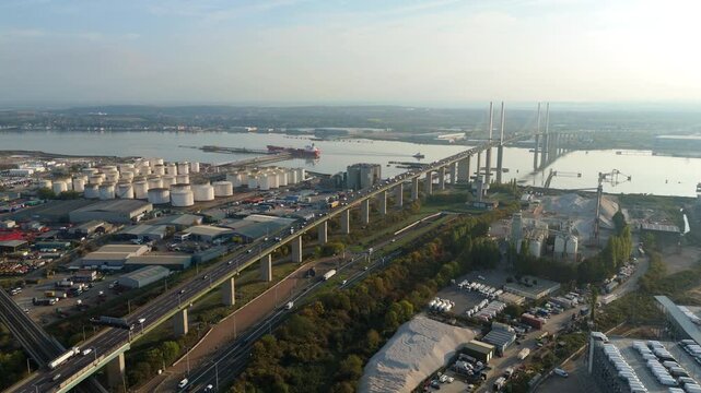 Aerial perspective of heavy industrial manufacturing complexes and petrochemical fuel storage silos on the Thames in Dartford, near crossing at sunset, United Kingdom 