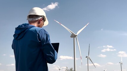 Engineer in helmet with laptop servicing wind turbines. Renewable wind energy technology concept. Engineer wind turbine for maintenance. Renewable energy solutions, wind turbine performance analysis. - Powered by Adobe