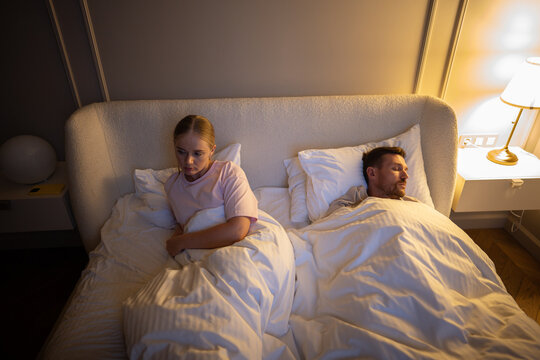 Exhausted wife unable to sleep at night from partner loud breathing in room. Sleep disruption, chronic fatigue in marriage, night insomnia, emotional strain from snore, lack of rest in relationship