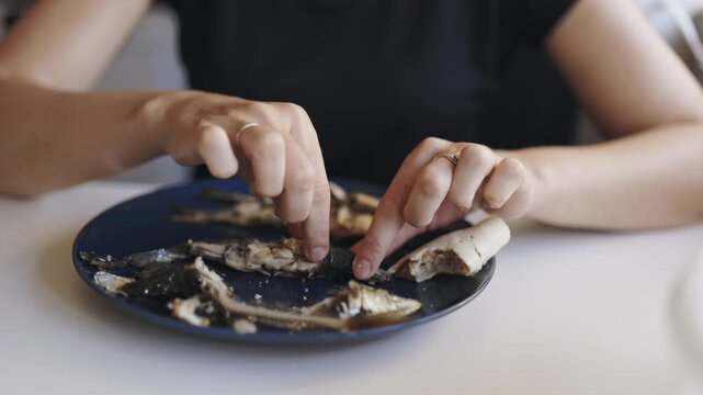 Woman eating grilled sardines with hands
