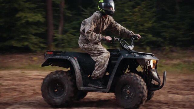 muddy ground, forest dirt, terrain driving. Driver on ATV leans into sharp turn on forest path, dirt flying everywhere.