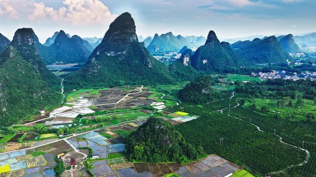 Aerial shot of the beautiful rural landscape with green paddy fields, villages, and spectacular karst mountain scenery in Guilin, China.