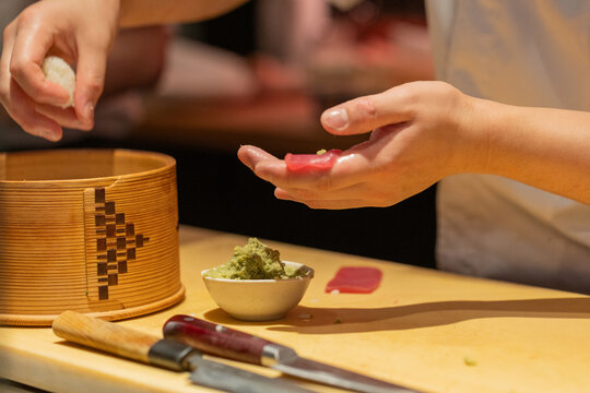 Sushi chef preparing fresh fish with wasabi on wooden countertop